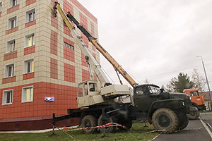 Două camioane cu macarale din Rusia, puse să susţină faţada unei clădiri, pentru a nu fi luată de vânt