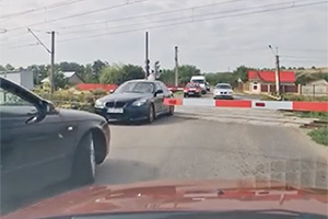 (VIDEO) Semafoarele roşii şi barierele de la o trecere de cale ferată din Răcăciuni, România, ignorate de 9 şoferi şi 2 biciclişti în nici două minute