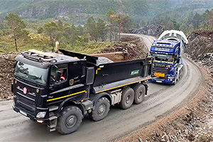 (VIDEO) Un camion Tatra şi unul Scania fac echipă pentru a urca în tandem 105 tone agabaritice pe un vârf de deal, fără asfalt
