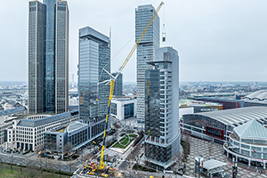 O macara Liebherr uriaşă, pe platformă de camion, a ridicat tone de echipament pe acoperişul unui zgârie-nori din Frankfurt, într-o lucrare complexă şi emblematică